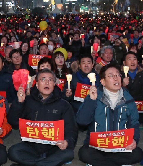 촛불시위에 참가한 문재인과 이재명이 박근혜 대통령 탄핵 피켓을 들고 있다.